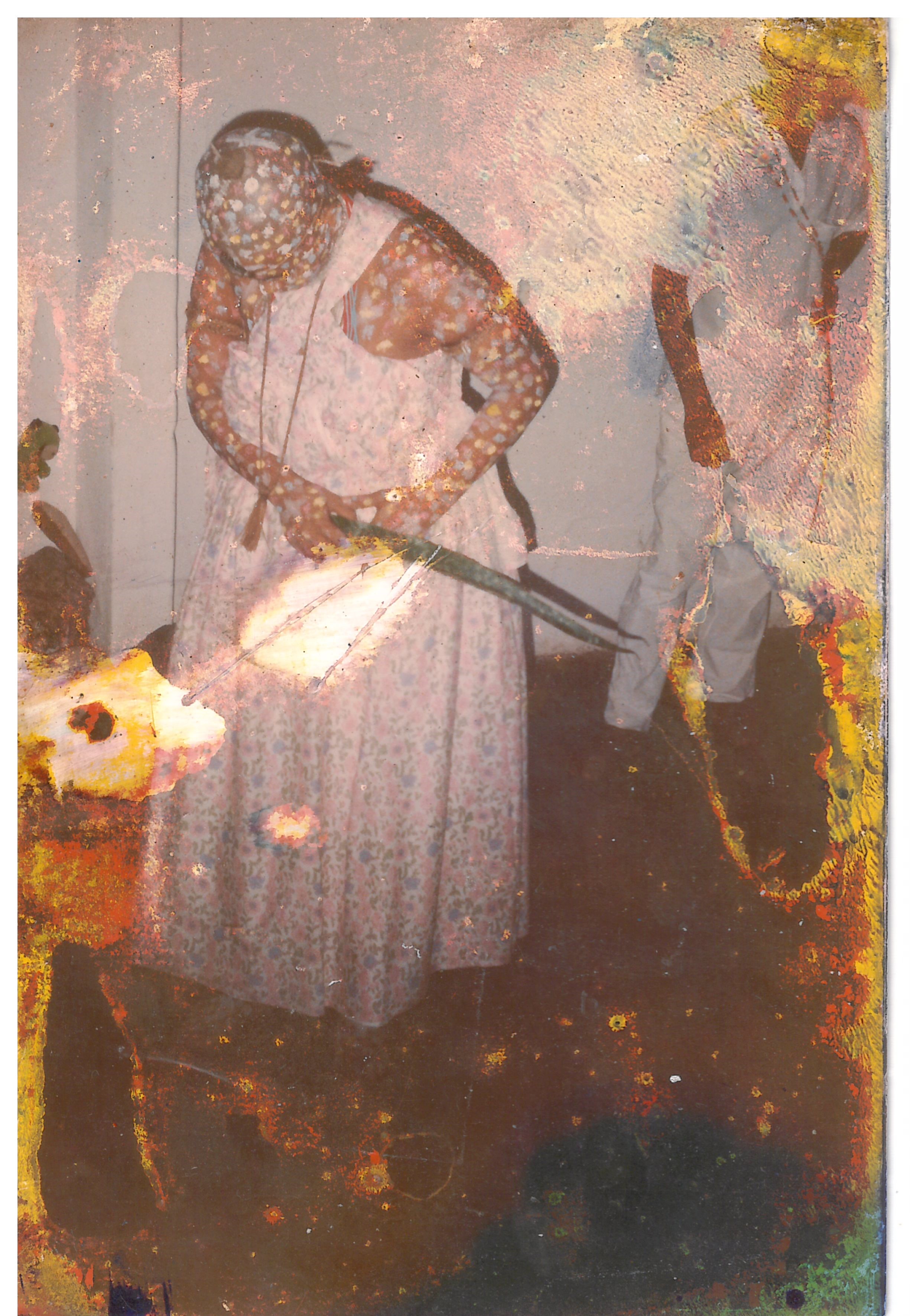 A imagem é uma fotografia antiga digitalizada e possui bastante marcas do tempo nas bordas. A foto registra a “saída de sua orixá”, simbolizando a vitória e a renovação. Mãe Anna está ao centro, com cabelo raspado, com um vestido branco longo, com a cabeça virada para baixo, sua cabeça e seu corpo estão pintados e segura nas mãos uma folha de espada de São Jorge. Ao fundo uma parede branca e um rapaz vestido também de branco.