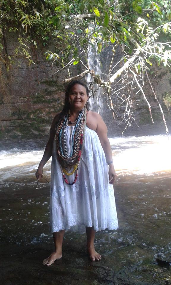 Na fotografia Mãe Anna aparece com indumentária de religião de Matriz Africana, uma saia branca , roupa tradicionalmente usadas no terreiro, que visualmente fica similar há um vestido sem alças. Mãe Anna está aos pés de uma cachoeira pequena, a beira de um lago em que as águas estão dando a entender movimento. Na composição da imagem ela aparece de corpo inteiro, ao fundo o lago, a cachoeira e alguns galhos de árvores.
